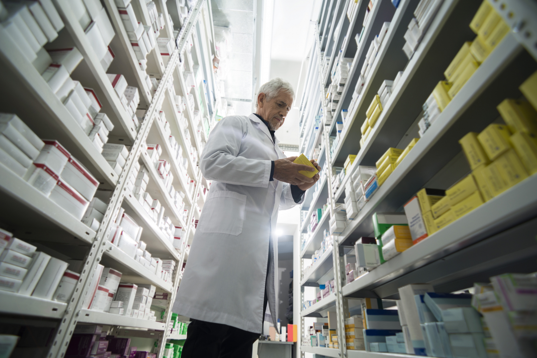 19806644-senior-male-chemist-standing-by-shelves-in-pharmacy